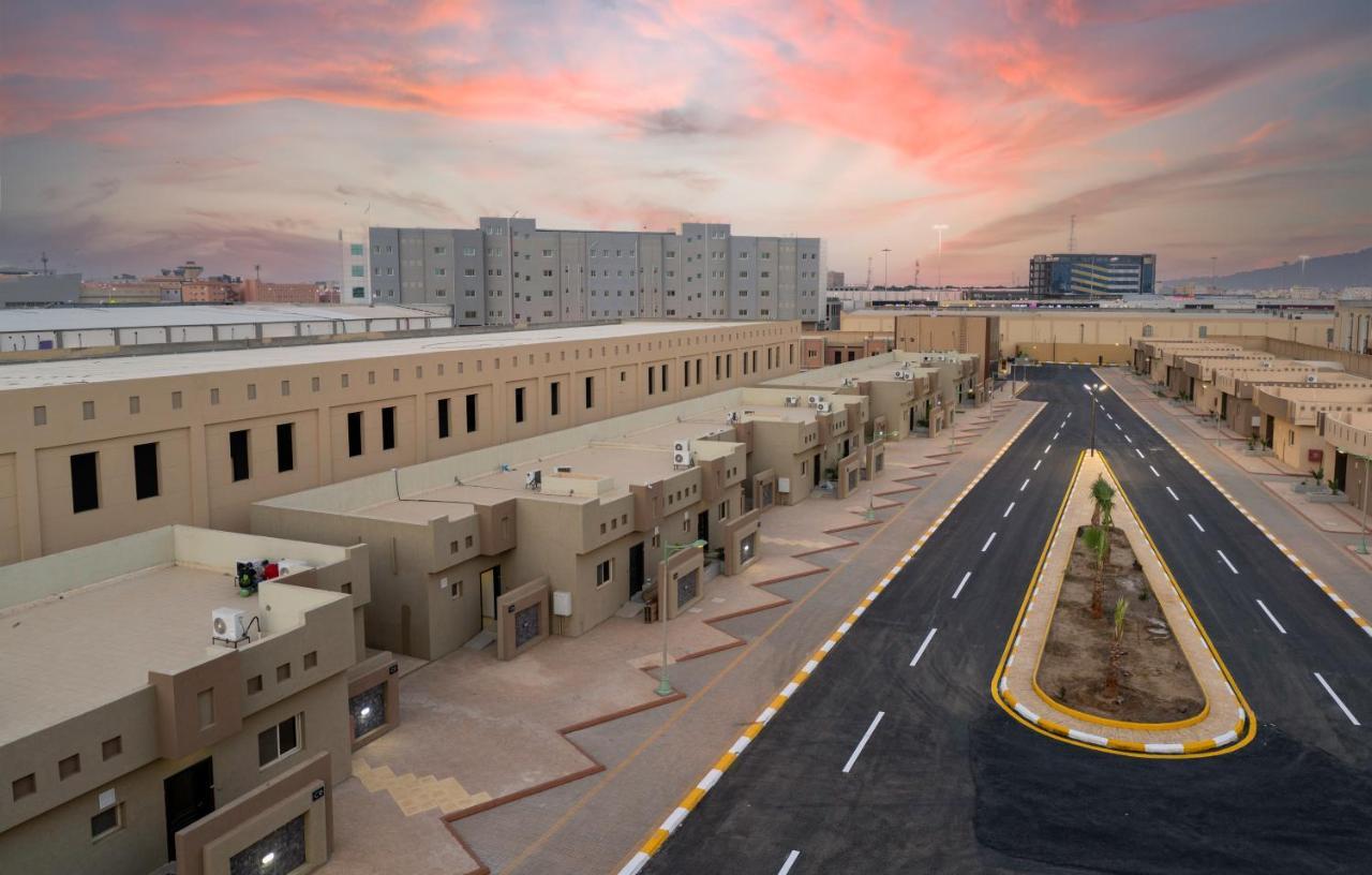 Mirada Gold Jizan - Resort & Private Pools 外观 照片 The photo shows a modern residential area with a series of light-colored buildings lined along a road. The architecture appears to be contemporary, featuring low-rise structures that include individual homes or apartments. The street is well-maintain